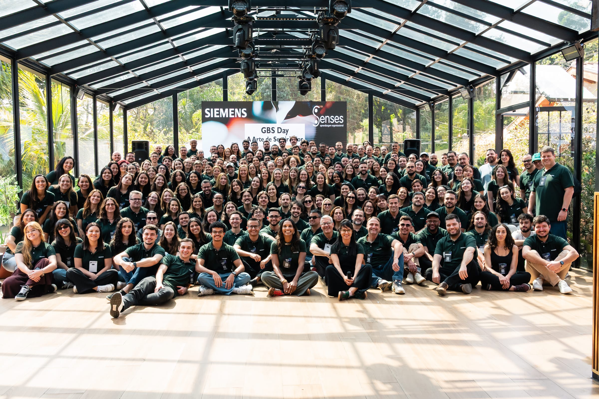 Equipe de uma empresa reunida para a foto do evento no salão de vidro.